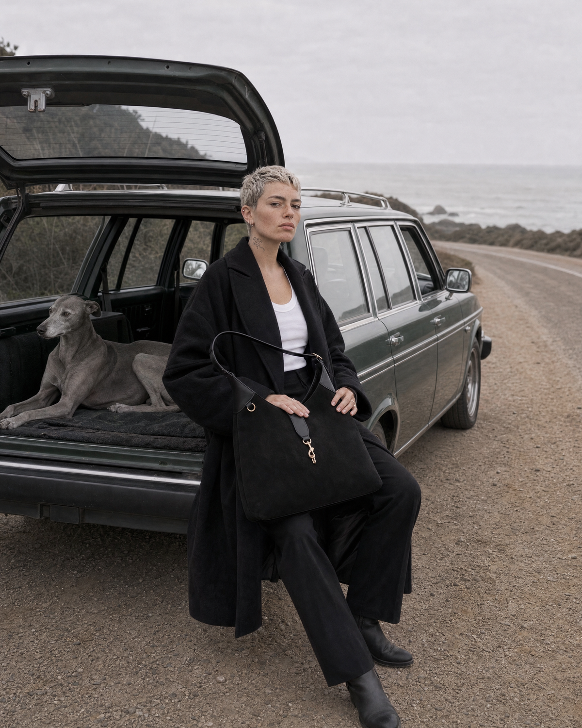 Woman sitting in the tailgate of an old car with The Brume Clip Hobo in Noir