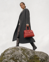 Woman on a granite boulder carrying The Aurore Briefcase in Rouge