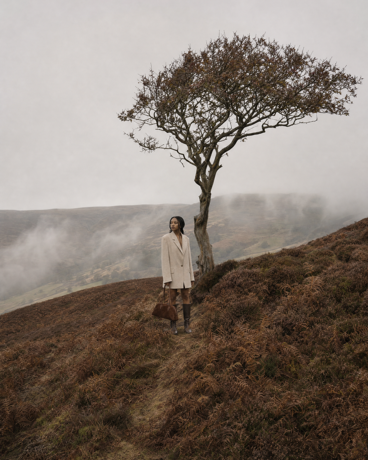 Woman under a lone tree on a misty moor with The Brume East-West in Chocolate