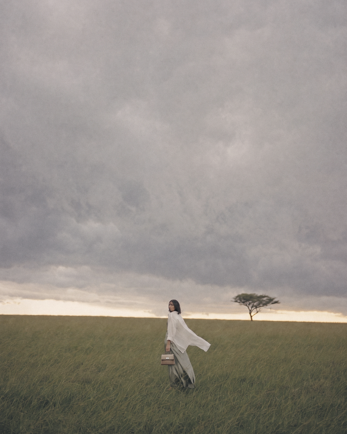 Woman in a vast green savanna with The Brise in Taupe