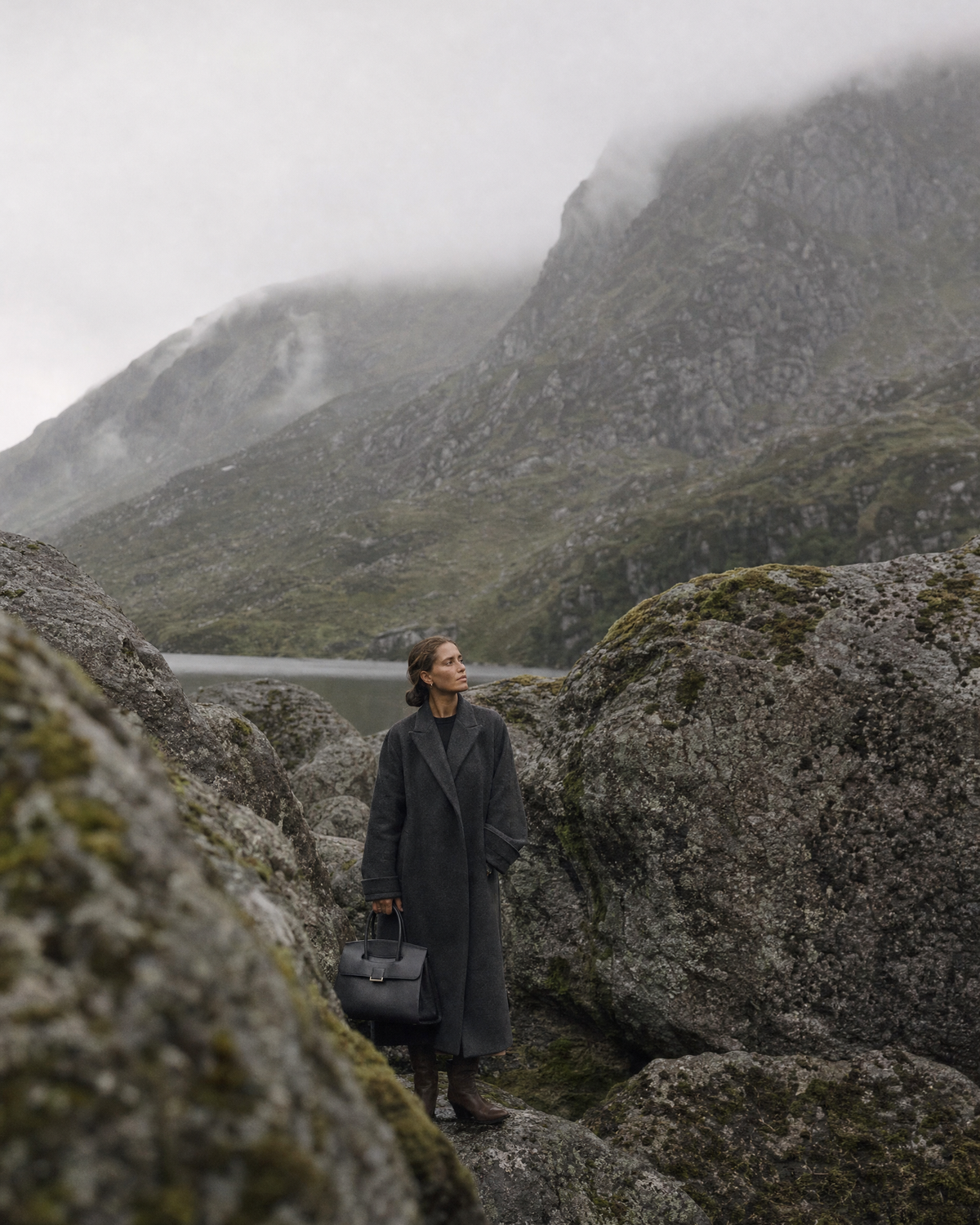 Woman among giant boulders with The Aurore Briefcase in Noir