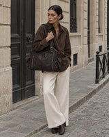 The Estran in Espresso, worn on the shoulder on a quiet stone street