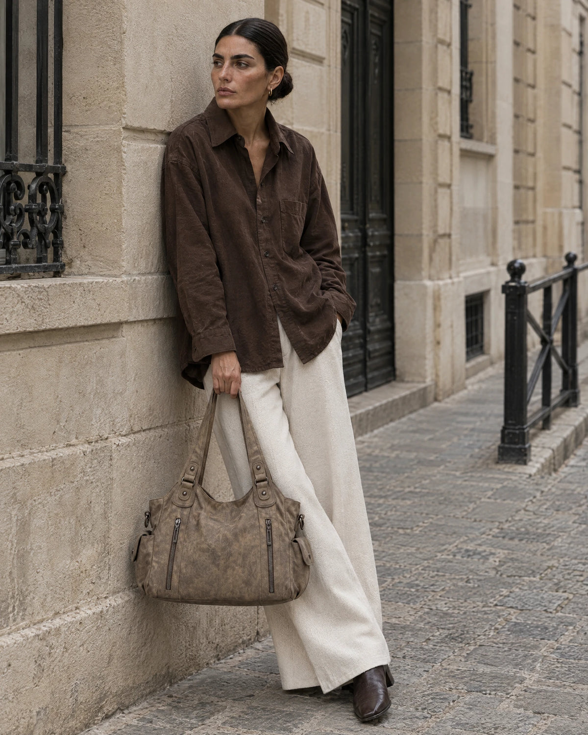 The Estran in Sable, worn on the shoulder on a quiet stone street