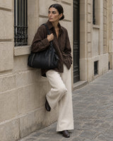 The Estran in Noir, worn on the shoulder on a quiet stone street