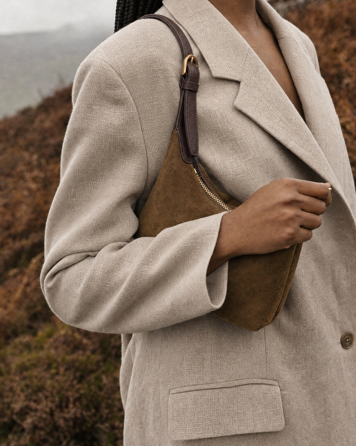 Hand opening the gold zip of The Brume Petite in Tabac