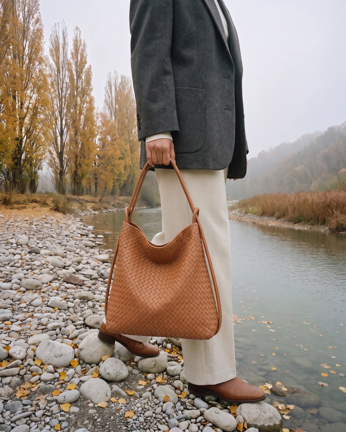 The Embellie in Cognac, woven leather tote carried by the double cord handle by the river