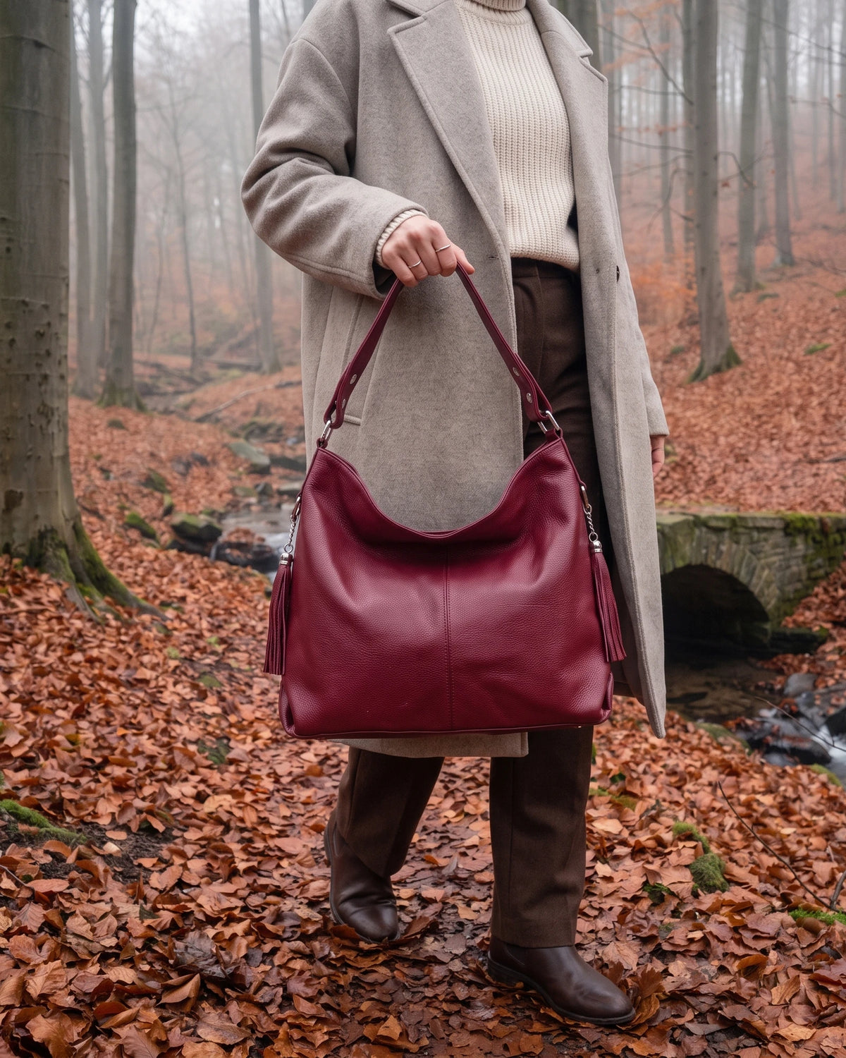 The Houle Soft in Bordeaux, berry bordeaux leather hobo bag carried by the short handle in a misty autumn beech forest