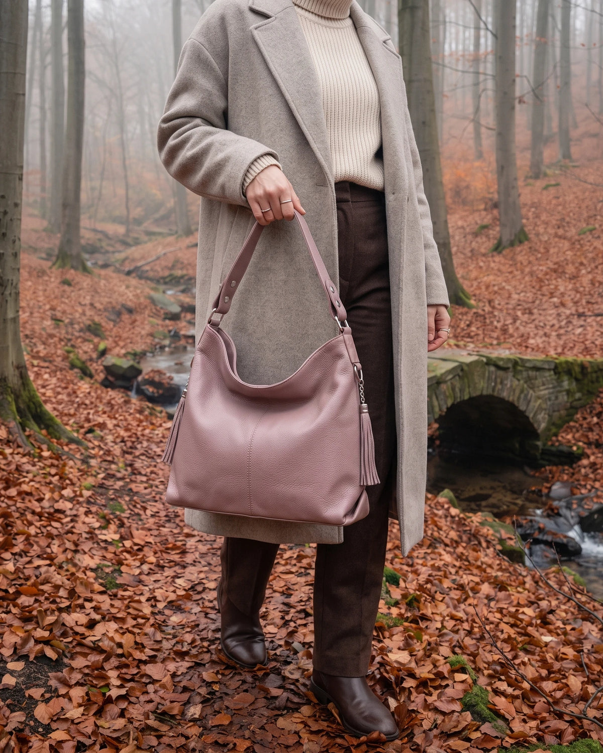 The Houle Soft in Rose, dusty rose leather hobo bag carried by the handle in a misty autumn beech forest