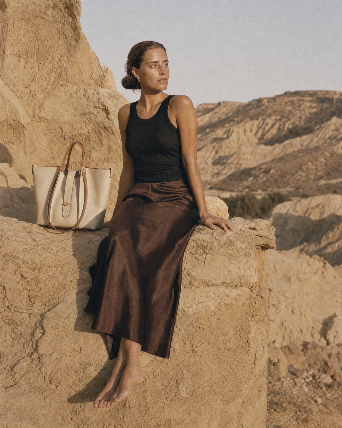 Woman sitting on a sandstone ledge next to The Havre Buckle in Écru