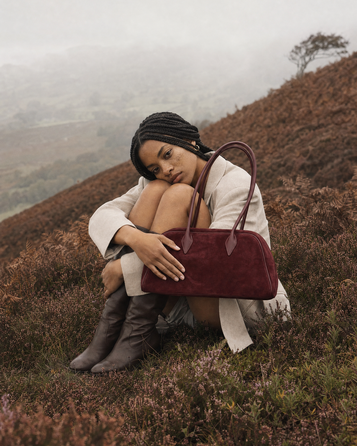 Woman sitting in the heather with The Brume East-West in Bordeaux on her knees