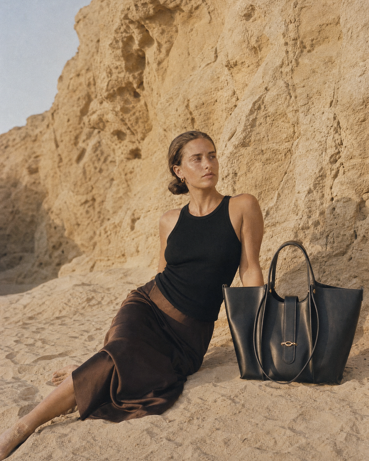 Woman sitting on a sandstone ledge next to The Havre Buckle in Noir
