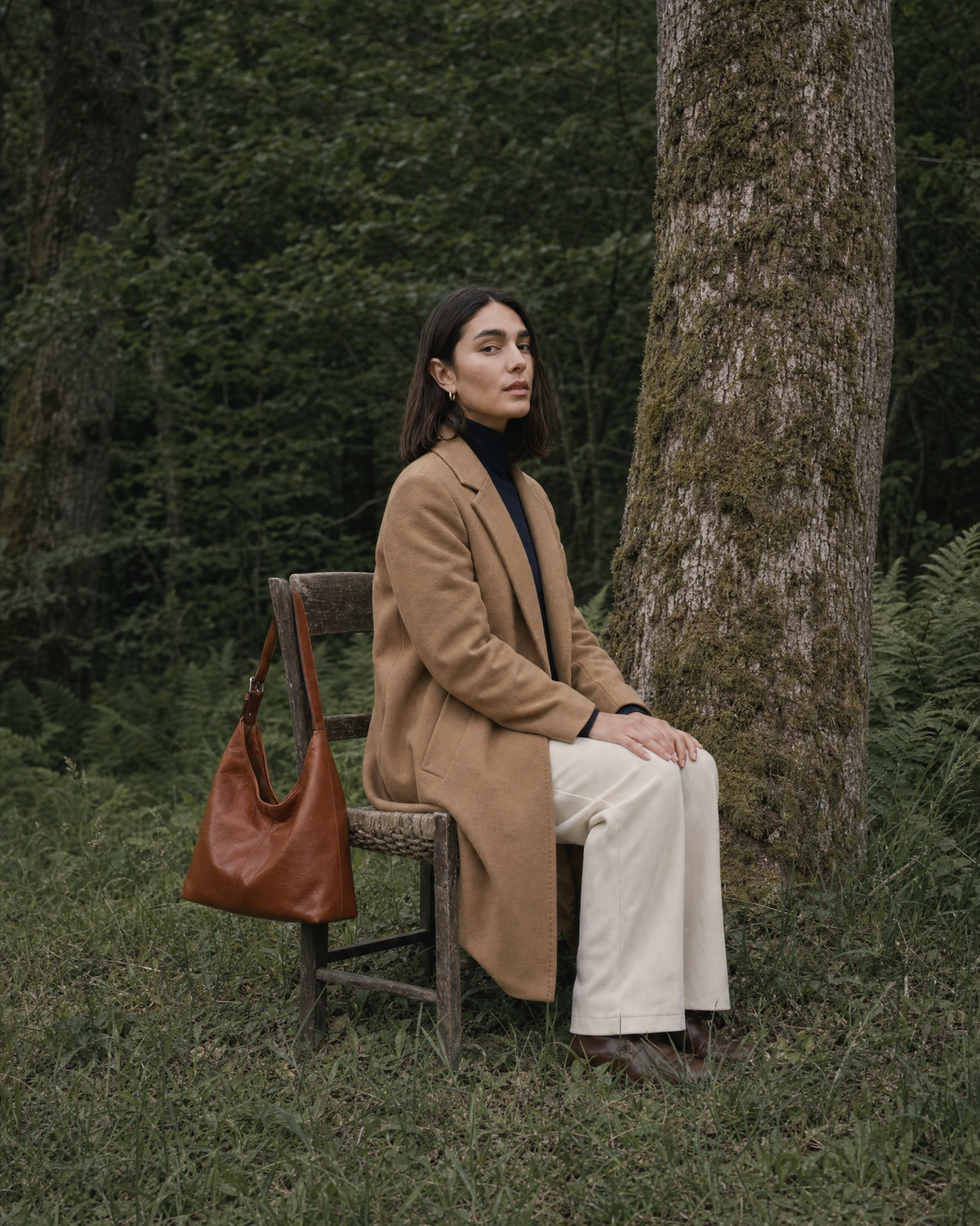 Woman sitting on a wooden chair under an oak, The Houle in Cognac hanging from the chair