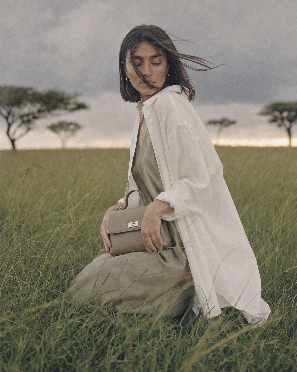 Woman kneeling in tall grass with The Brise in Taupe