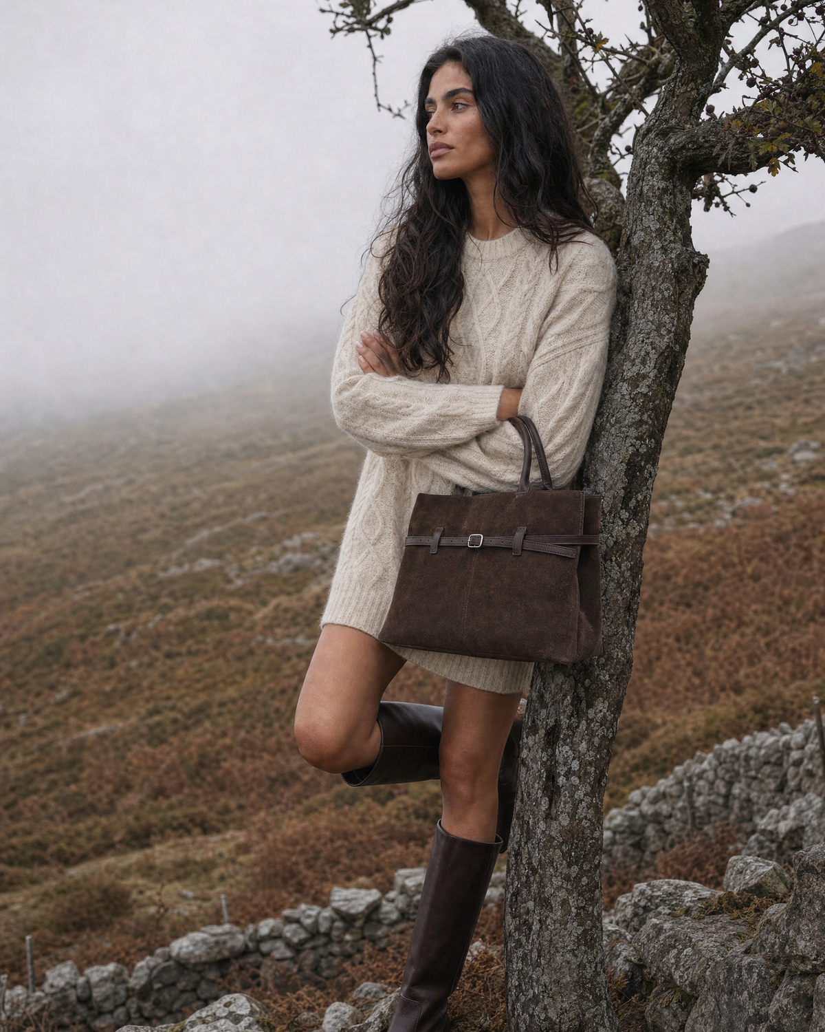Woman by a dry-stone wall with The Brume Belted Tote in Chocolate