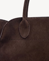 The Aurore Suede Satchel in Espresso, oval handle tab and topstitching detail