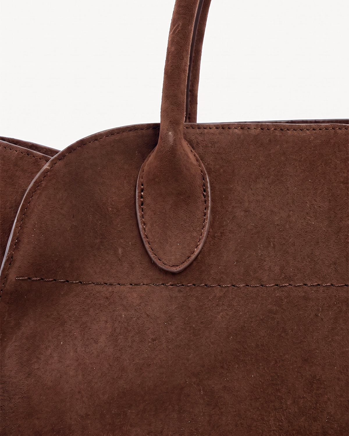 The Aurore Suede Satchel in Chocolate, oval handle tab and topstitching detail