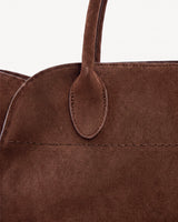 The Aurore Suede Satchel in Chocolate, oval handle tab and topstitching detail
