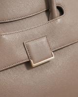 Close-up of the square gold plate on the flap of The Aurore Briefcase in Sable