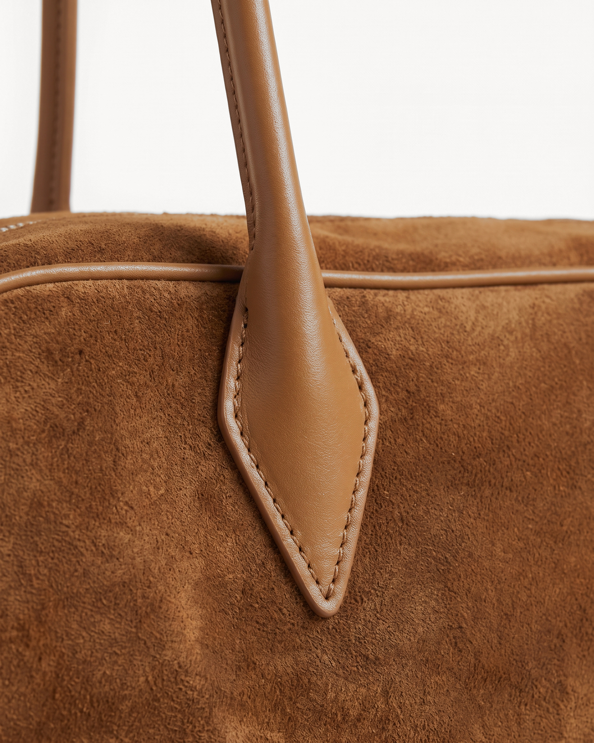 Close-up of the pointed leather tab and long handle of The Brume East-West in Tabac