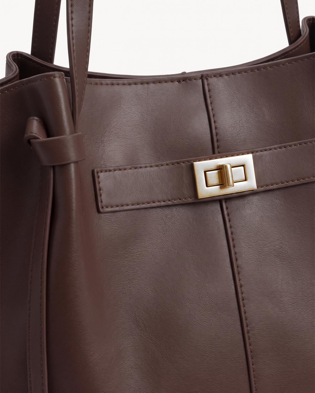 Close-up of the gold turn-lock on The Aurore Wing in Espresso