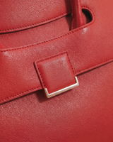 Close-up of the leather tab and gold buckle on the flap of The Aurore Briefcase in Rouge