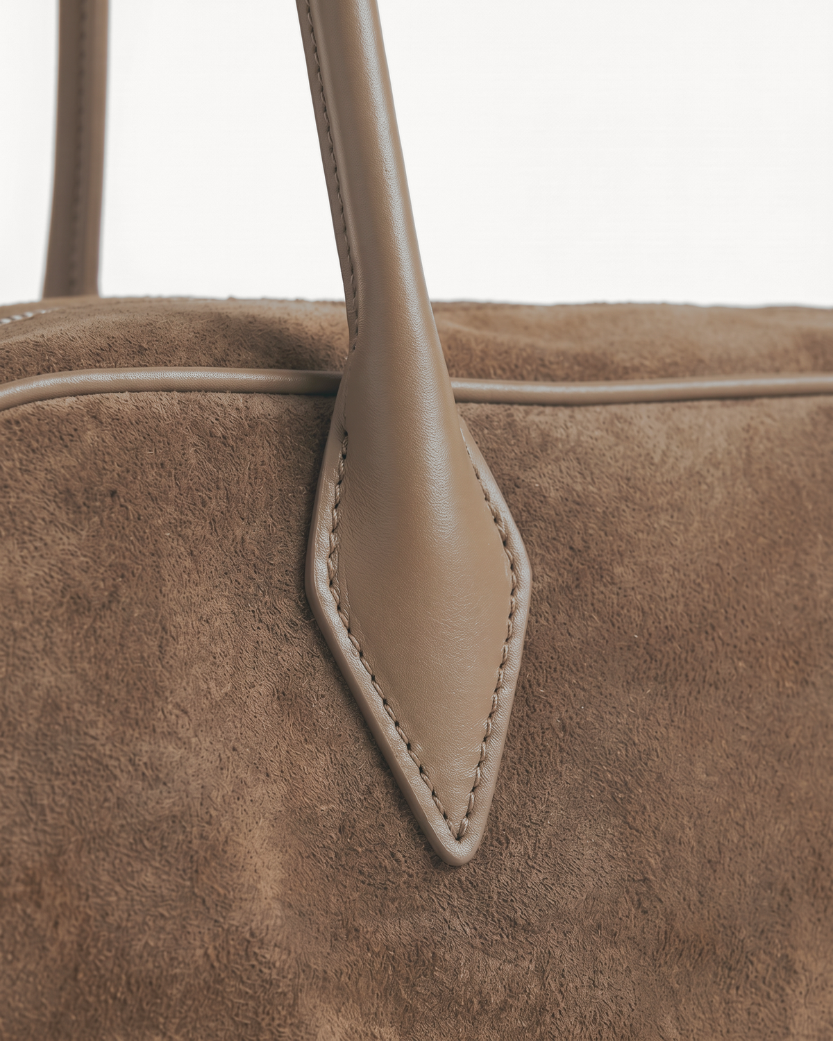 Close-up of the pointed leather tab and long handle of The Brume East-West in Galet