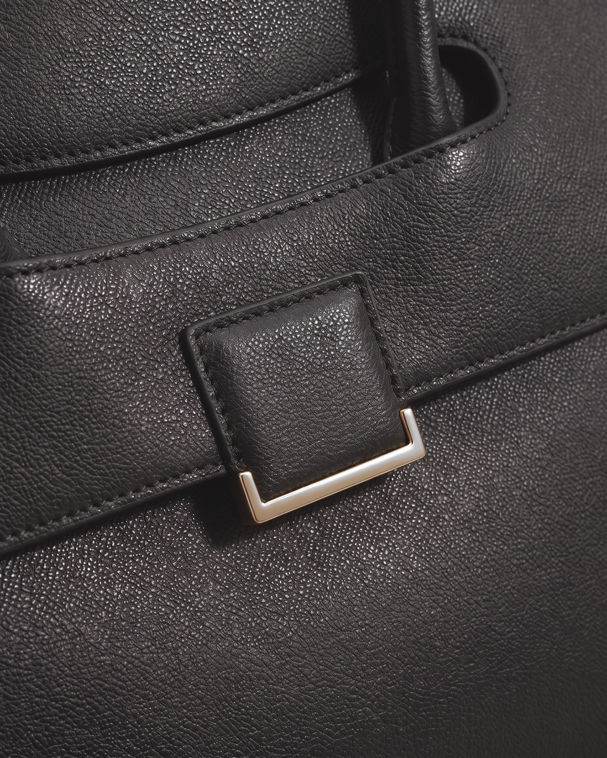 Close-up of the leather tab and gold buckle on the flap of The Aurore Briefcase in Noir