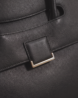 Close-up of the leather tab and gold buckle on the flap of The Aurore Briefcase in Noir