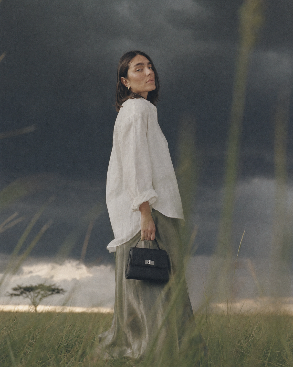 Woman standing in tall grass holding The Brise in Noir