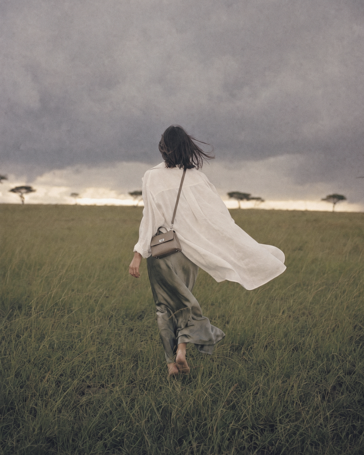 Woman walking into the storm wearing The Brise in Taupe crossbody