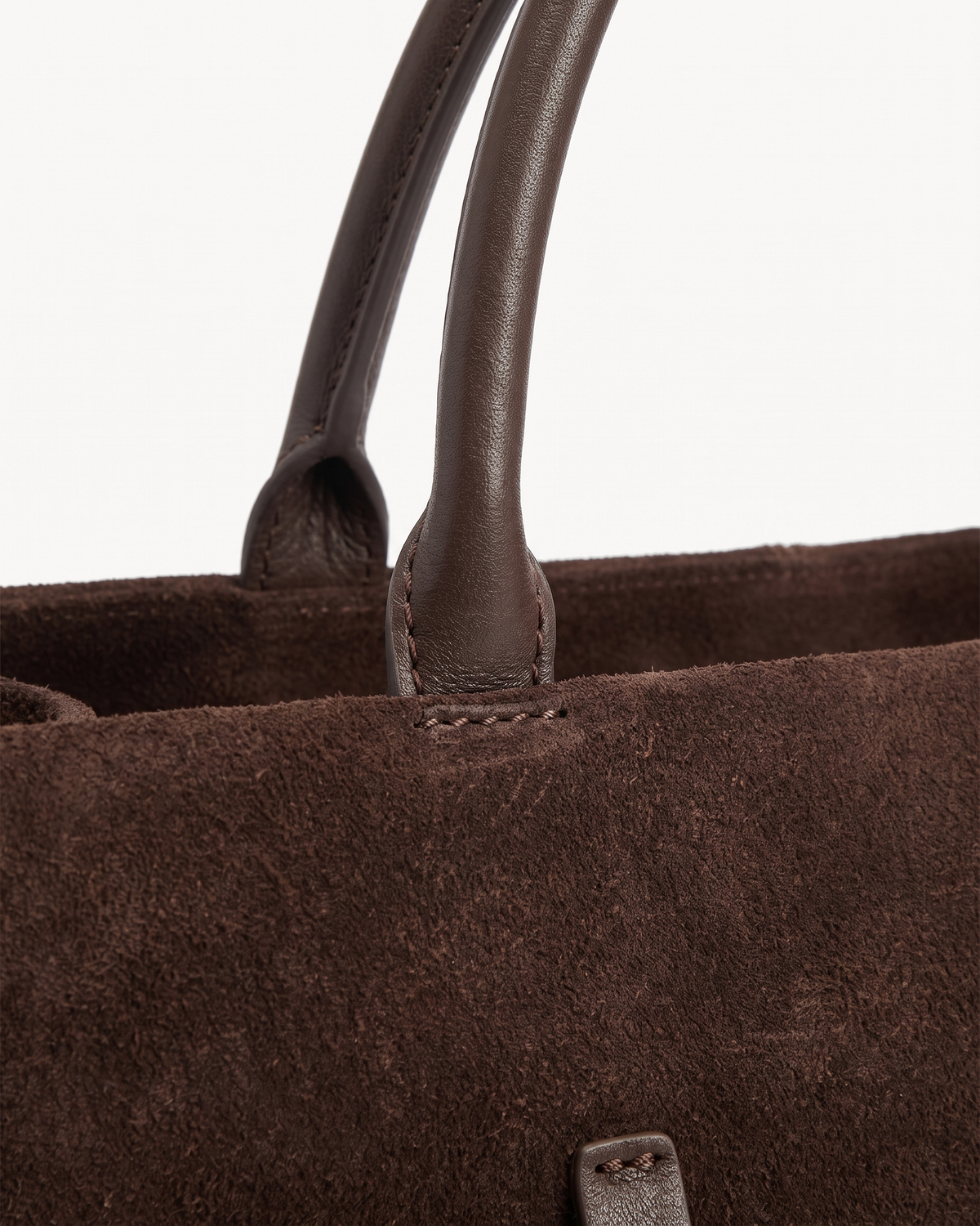 Close-up of the rounded leather handles of The Brume Belted Tote in Chocolate