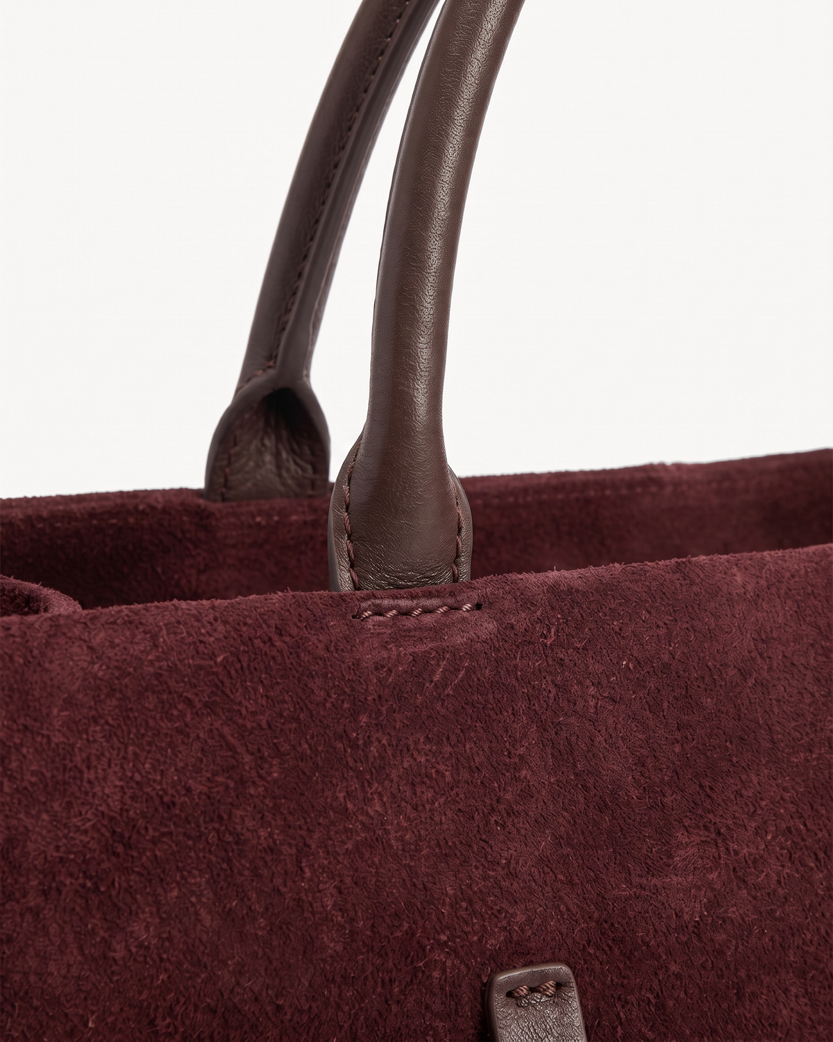 Close-up of the rounded leather handles of The Brume Belted Tote in Bordeaux