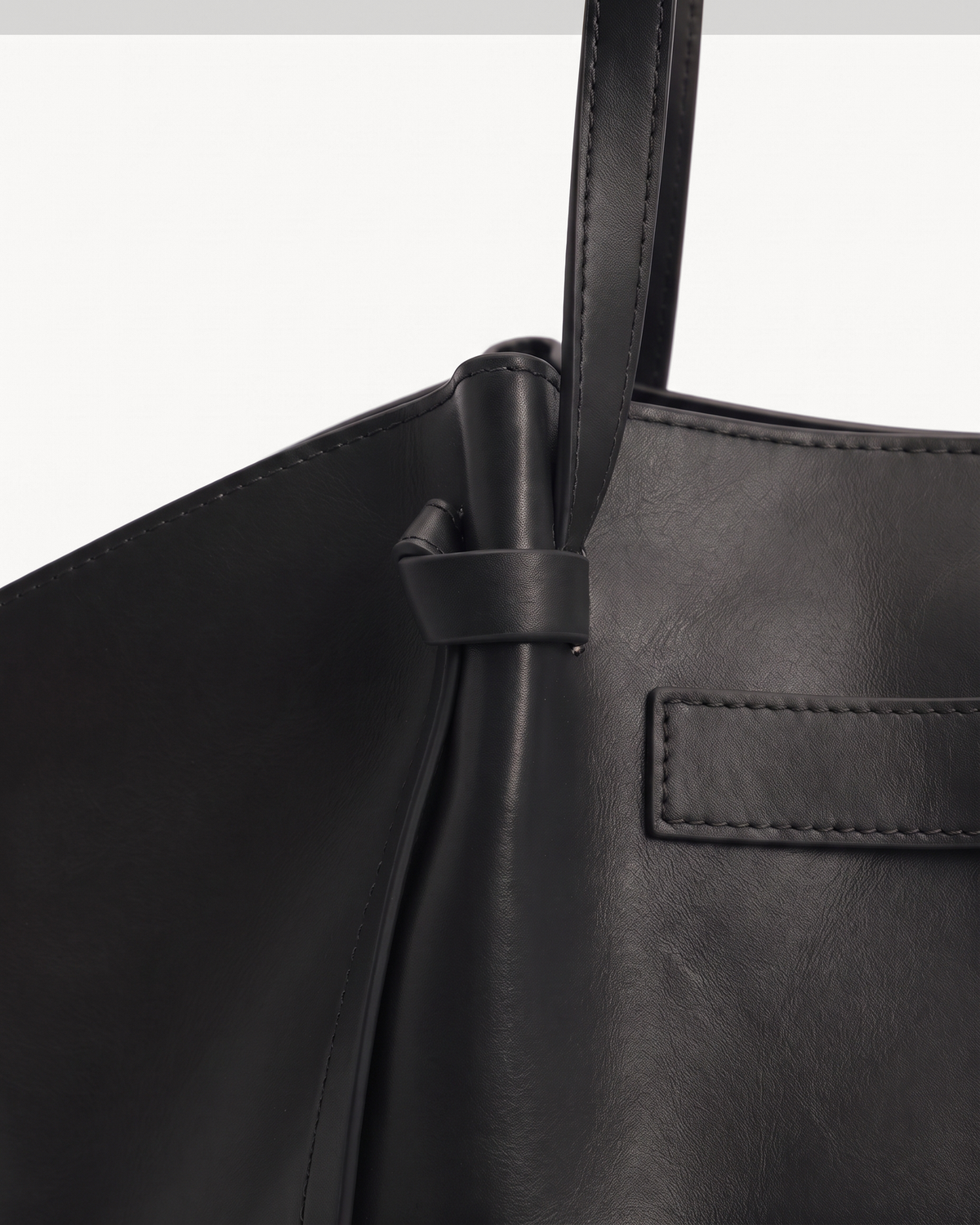 Close-up of the knotted tab and handle of The Aurore Wing in Noir