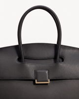 Close-up of the top handle passing through the flap of The Aurore Briefcase in Noir
