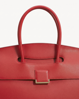 Close-up of the top handle passing through the flap of The Aurore Briefcase in Rouge