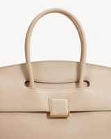Close-up of the top handle passing through the flap of The Aurore Briefcase in Écru