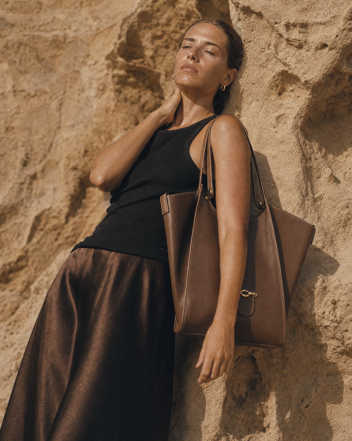 Woman leaning against a sandstone wall with The Havre Buckle in Espresso