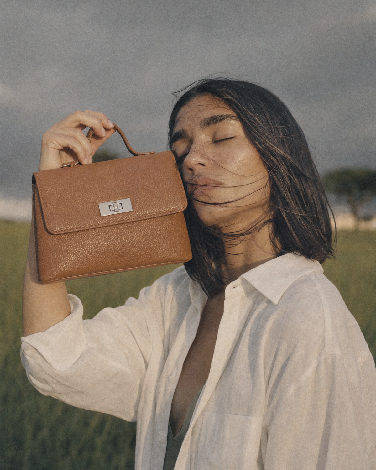 Woman holding The Brise in Cognac beside her face, eyes closed