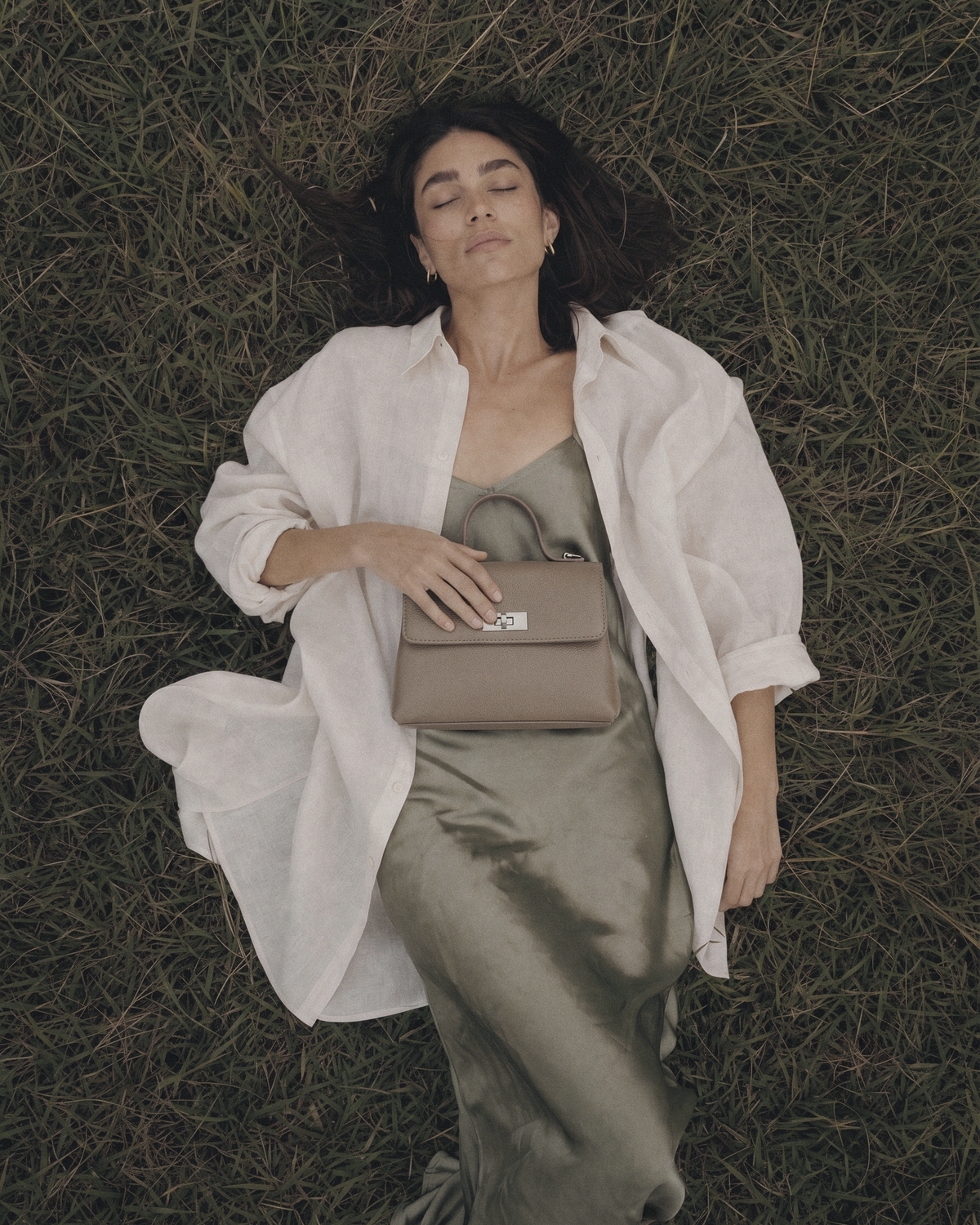 Woman lying in the grass with The Brise in Taupe