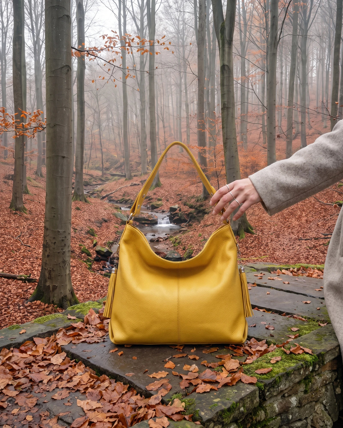 The Houle Soft in Citron, lemon yellow leather hobo bag standing on the mossy stones of a forest footbridge