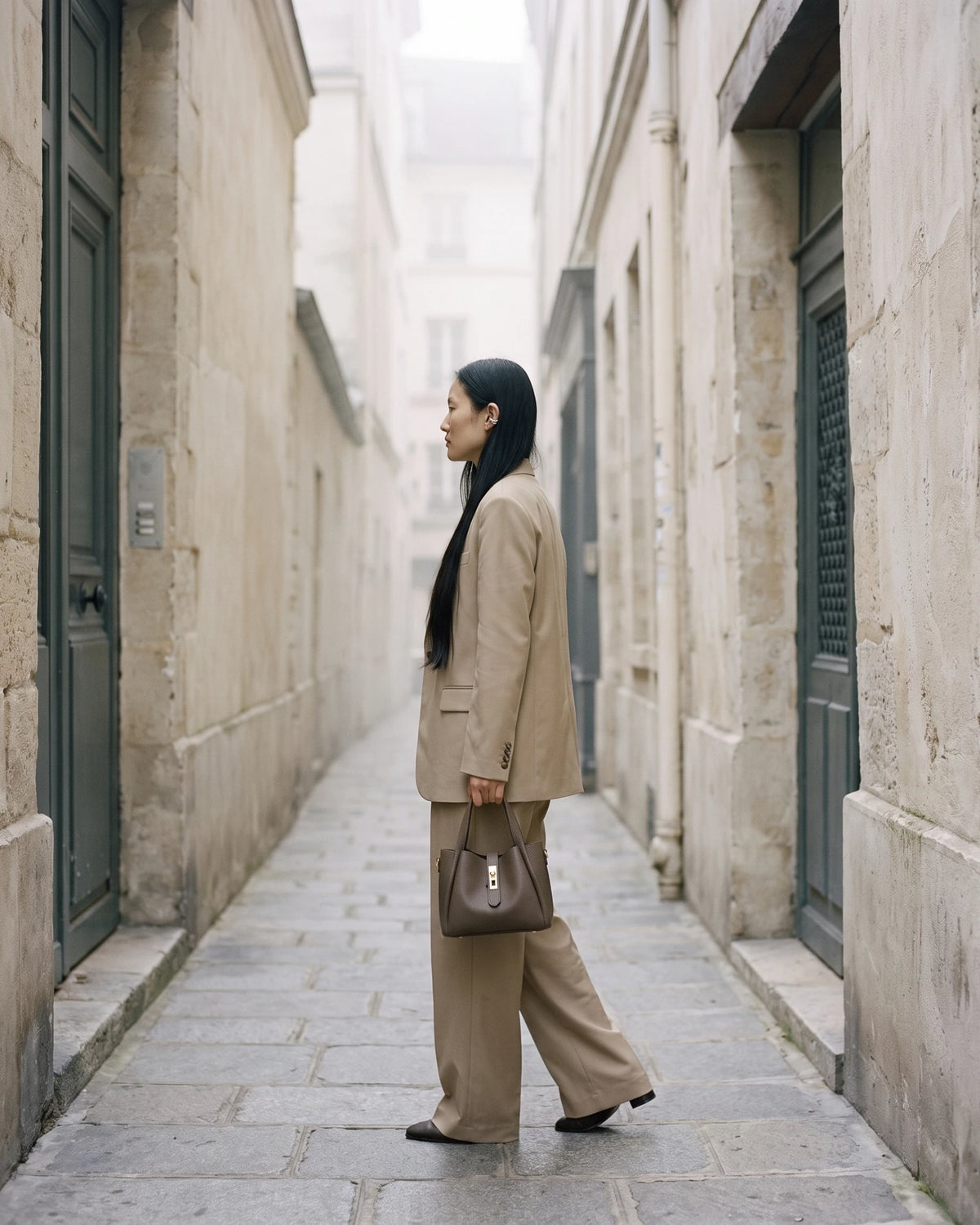 The Grève in Taupe carried by hand in a narrow stone street