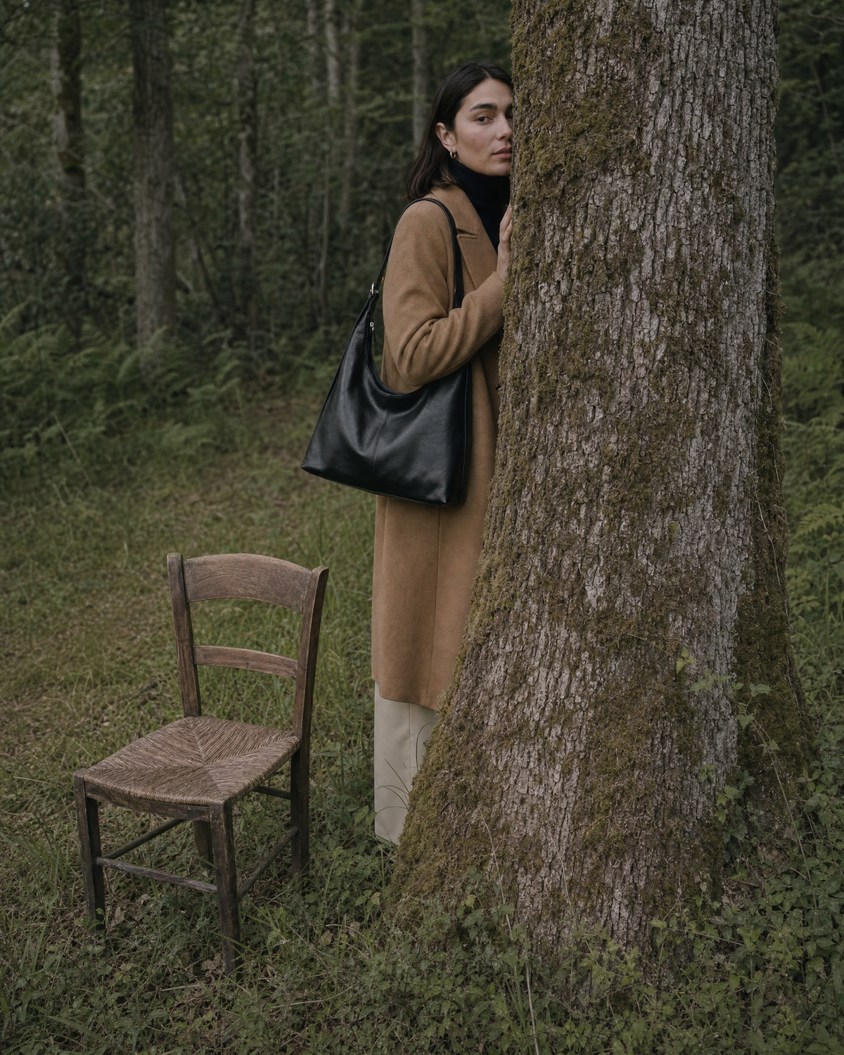Woman half hidden behind an old oak with The Houle in Noir on her shoulder