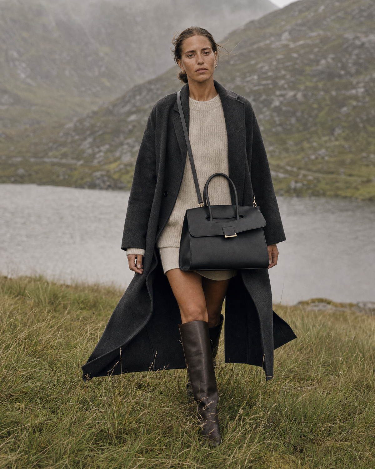 Woman walking through tall grass wearing The Aurore Briefcase in Noir crossbody