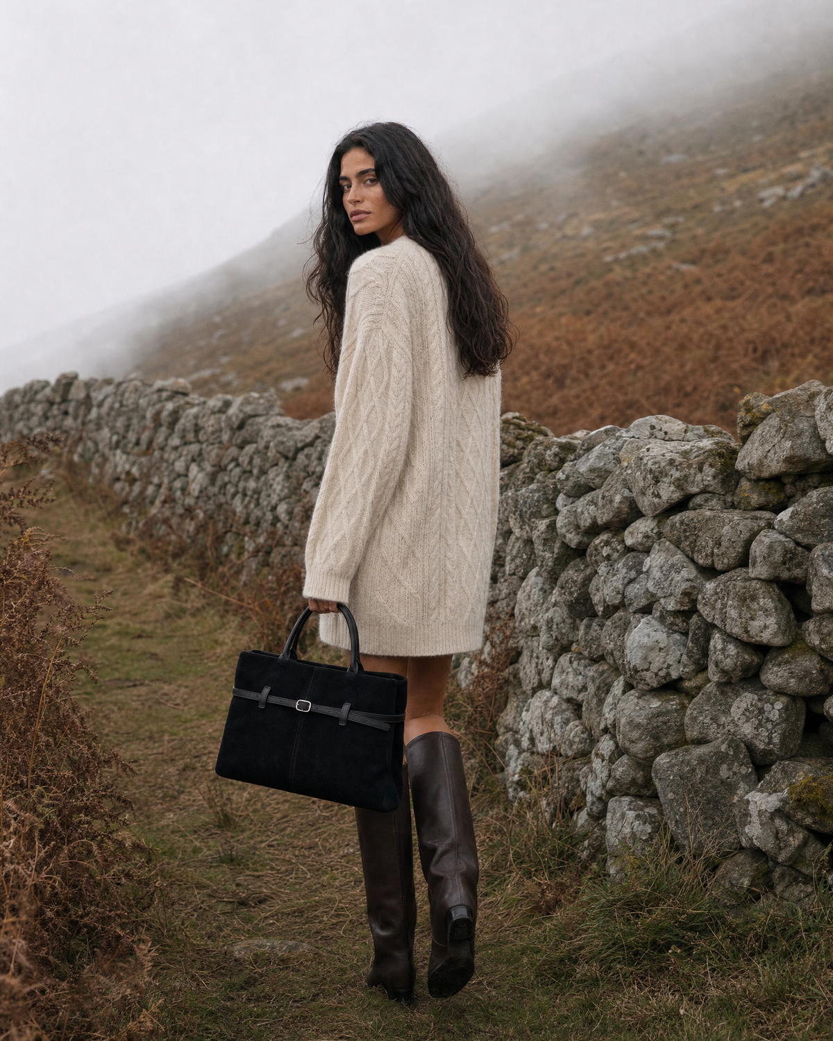 Woman walking across the heather with The Brume Belted Tote in Noir