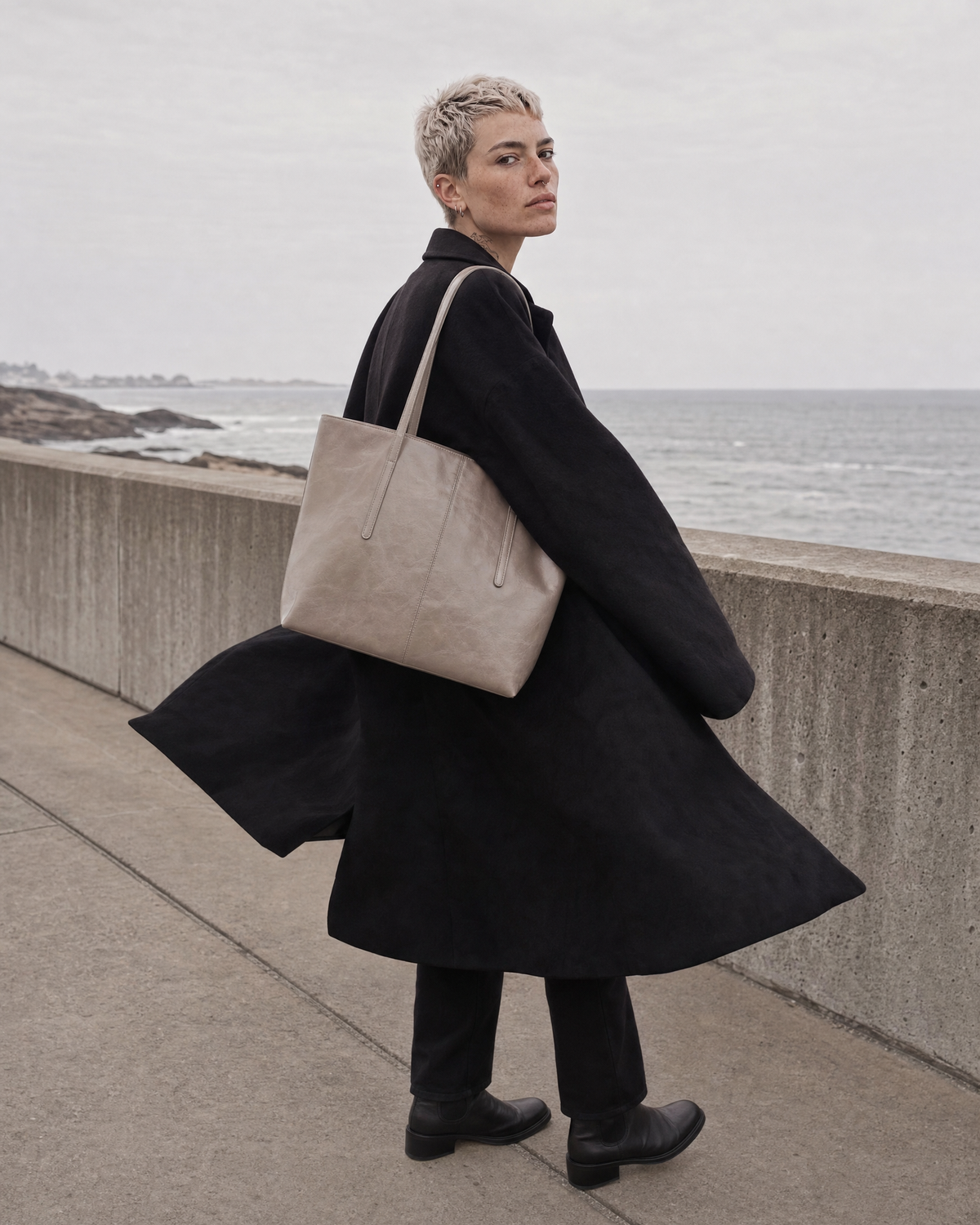 Woman turning in the wind on a sea wall with The Marée Grand in Galet