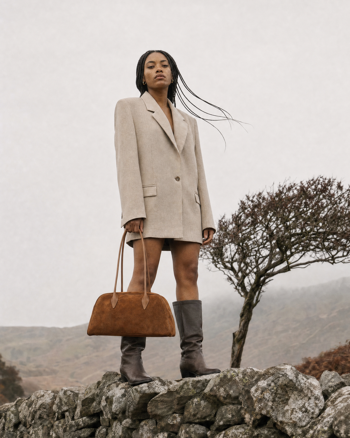 Woman standing on a dry-stone wall holding The Brume East-West in Tabac