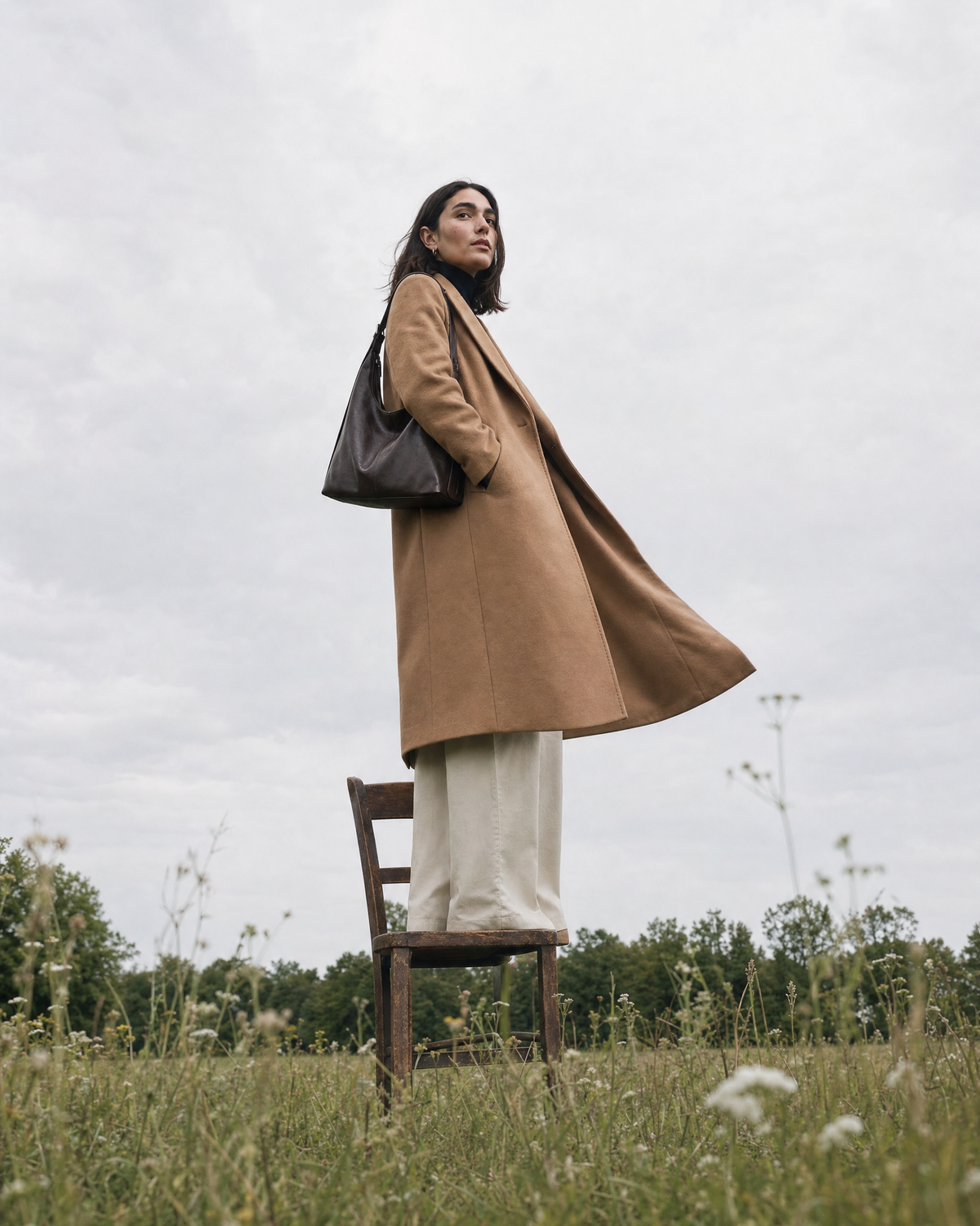 Woman standing on a wooden chair in a meadow with The Houle in Espresso