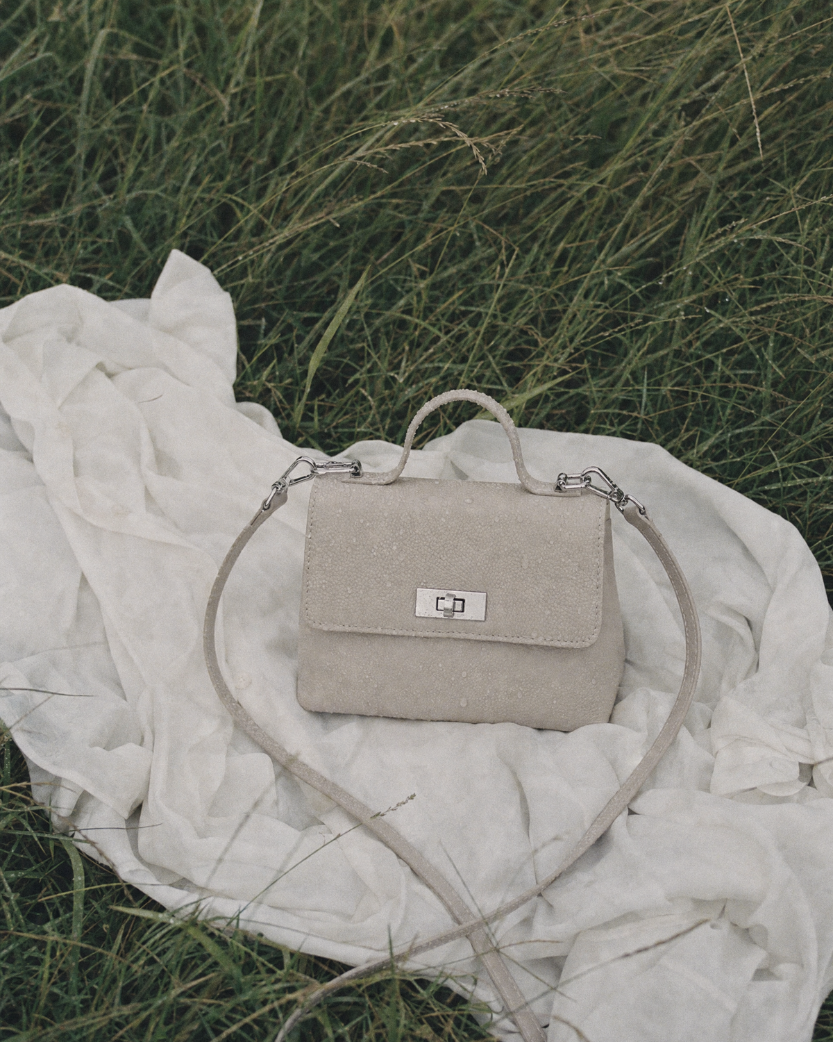 The Brise in Écru lying on a white shirt in the wet grass