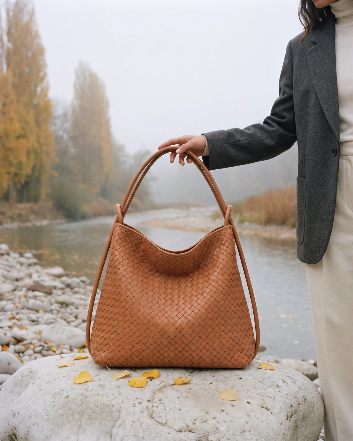 The Embellie in Cognac, woven leather tote standing on a river boulder