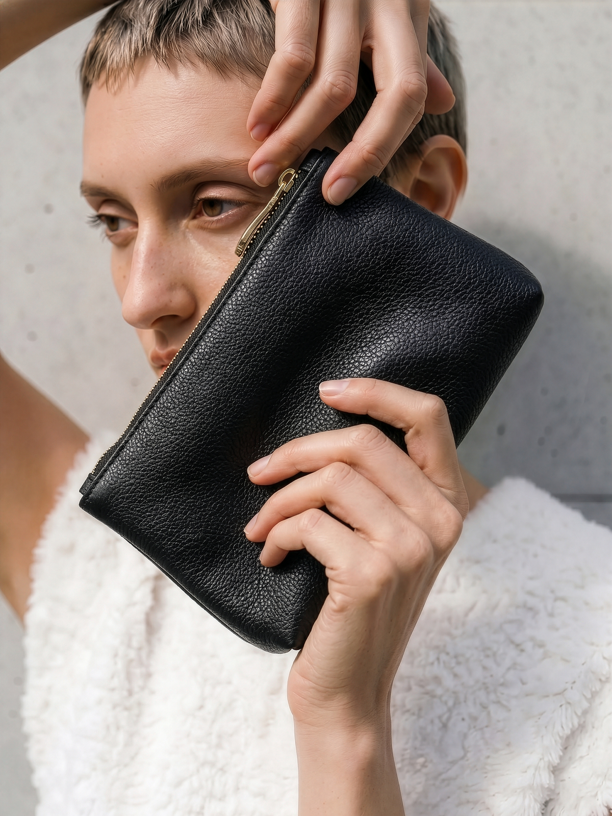 Woman holding the leather pouch of The Anse in Noir near her face